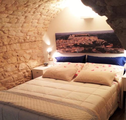 sypialnia z łóżkiem w kamiennej ścianie w obiekcie Al Borgo dell'Arte Suite w mieście Scicli