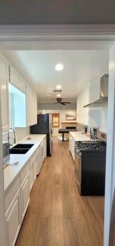a large kitchen with white cabinets and black appliances at Newly Furnished Pool House in Los Angeles