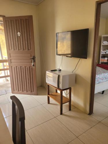 a room with a small table with a tv on a wall at Pousada Por Do Sol 2 andar in Palhoça