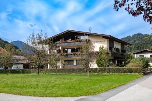 a building with a green lawn in front of it at Tirol Appartements Schwaiger in Niederndorf