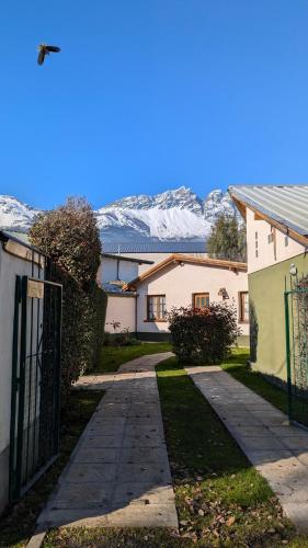 a house with a gate and snowy mountains in the background at Cabañas Willy in El Bolsón