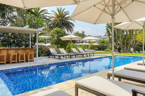 a swimming pool with chairs and umbrellas at Villa Coloniale Schumacher Luxury Retreat, Adults Only in Cape Town