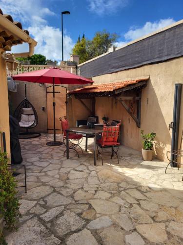 a patio with a table and chairs and an umbrella at Studio à deux pas du village in Ceyreste