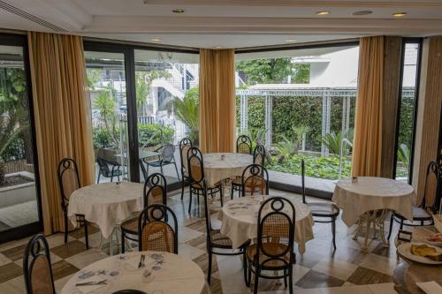 a restaurant with tables and chairs and large windows at Hotel President - Vintage Hotel in centro in Riccione