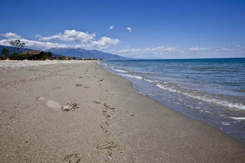 a beach with footprints in the sand and water at Golden Beach Sea View in Néa Meságkala