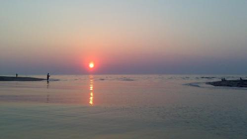 a person standing on the beach watching the sunset at Golden Beach Sea View in Néa Meságkala