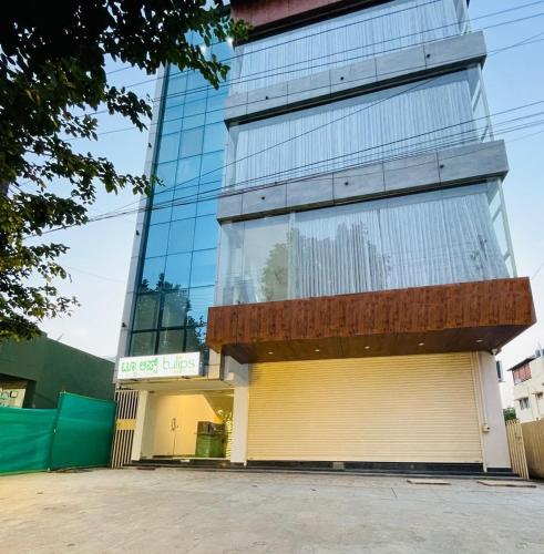 a tall glass building with a garage at Tulips Inn Mysuru in Mysore