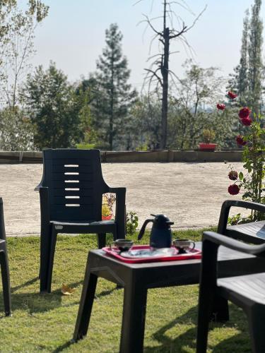 a chair and a table with a tea pot on it at Everest Guest House in Gulmarg