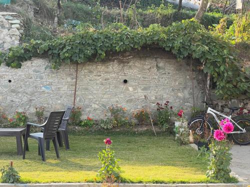 a garden with two chairs and a wall with flowers at Everest Guest House in Gulmarg