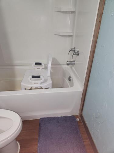 a white bathroom with a toilet and a bath tub at Skyfire Ranch in Caldwell