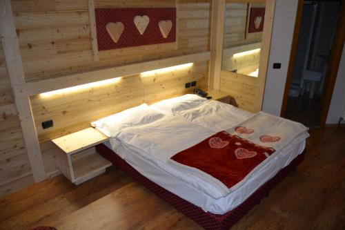a bed in a room with a wooden wall at Hotel Cova in Pellizzano