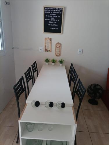 a white table with chairs in a room with a chalkboard at Cozy Home 1 in Boituva