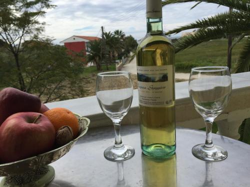 a bottle of wine and two glasses on a table at Family Studios in Marathias