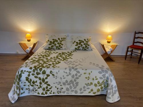 a bed with a green and white comforter and two lamps at Cottage 4 chambres avec cheminée in Épégard