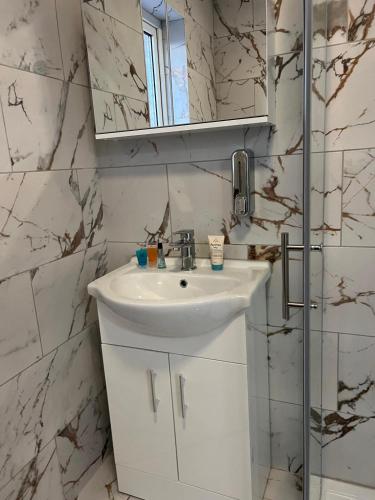a white bathroom with a sink and a mirror at Beautiful 2-bedroom in Grays close to Lakeside in Grays Thurrock