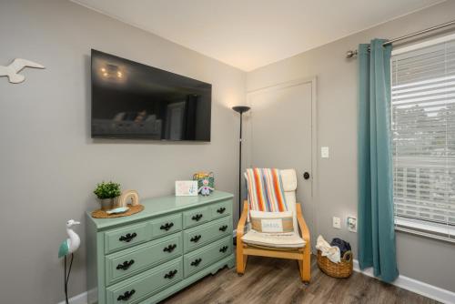 a bedroom with a dresser and a chair next to a window at The Islander- Luxurious Beach Property in Hilton Head Island