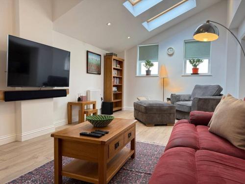 a living room with a red couch and a flat screen tv at April Cottage in Eastbourne