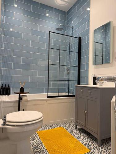 a blue tiled bathroom with a toilet and a sink at April Cottage in Eastbourne