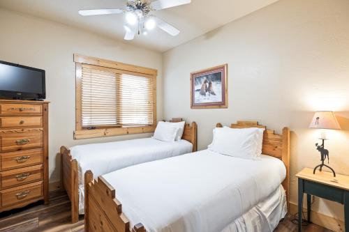 a bedroom with two beds and a tv and a dresser at Glenfiddich Condo, Deer Valley Resort, Cozy Interiors, Private Patio, Private Hot Tub, Stunning View in Park City
