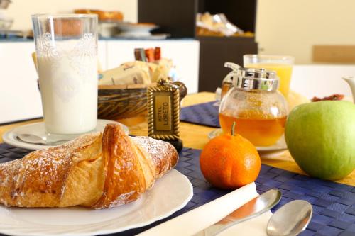 una mesa con un plato de cruasanes y un vaso de leche en Hotel Loreto, en Milán