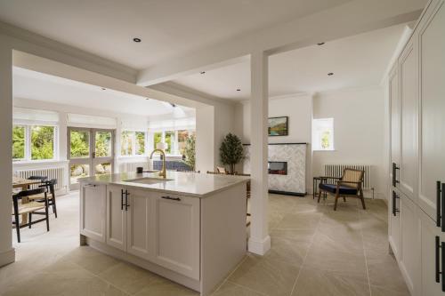 a kitchen with white cabinets and a dining room at Beaumont Exquisite Lakeland House, Sleeps 10 in Windermere