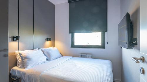 a bedroom with a bed with white sheets and a window at The Residence 59 in Belgrade
