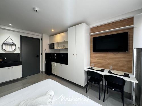 a kitchen with a table and a tv on a wall at Get By Side - Jardim Oceania in Tambaú