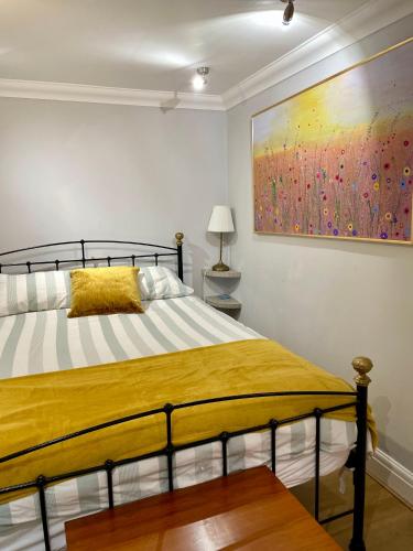 a bedroom with a bed with a painting on the wall at 3-bed cottage in Sway, New Forest (5 min walk from Sway Train Station) in Sway