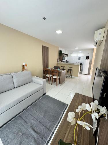 a living room with a grey couch and a kitchen at Mandai Apartamentos in Cabo Frio