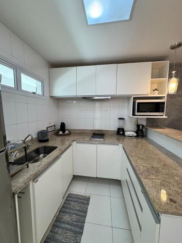 a kitchen with white cabinets and a sink at Mandai Apartamentos in Cabo Frio