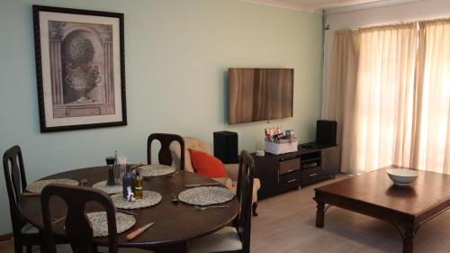 a living room with a table and a dining room at Strand Beach Townhouse Self Catering in Cape Town
