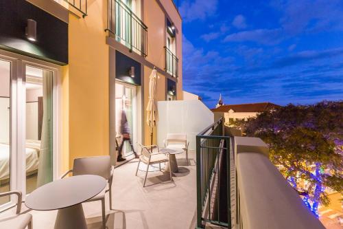 a balcony of a building with chairs and tables at Castanheiro Boutique Hotel in Funchal