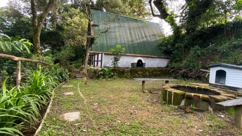 a house with a green roof and a bench at Cabañita del bosque de la cumbre de san Bartolo Milpas Altas in Guatemala
