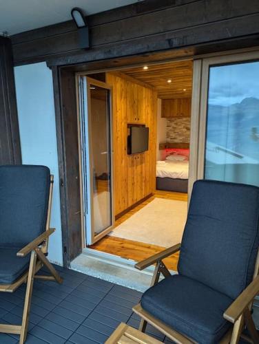 two chairs and a television on a balcony with a bedroom at Studio Le Chamois - Veysonnaz in Veysonnaz