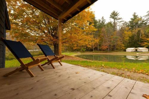 two benches sitting on a wooden deck near a pond at Madbush Falls in Waitsfield
