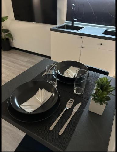a table with two black plates and silverware on it at Royal B&B in Lonate Pozzolo