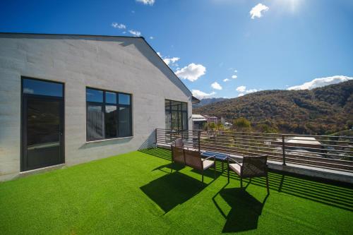 a house with two chairs on a balcony with green grass at Dili Dream Villa in Dilijan