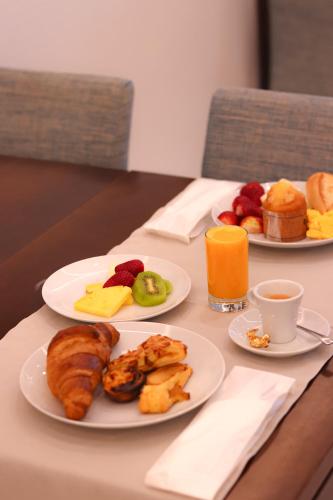 two plates of breakfast foods on a table with orange juice at Hotel Concha in São Martinho do Porto