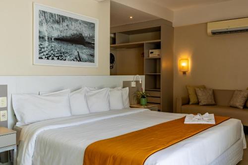 a hotel room with a large bed and a couch at eSuites Lagoa Santa in Lagoa Santa