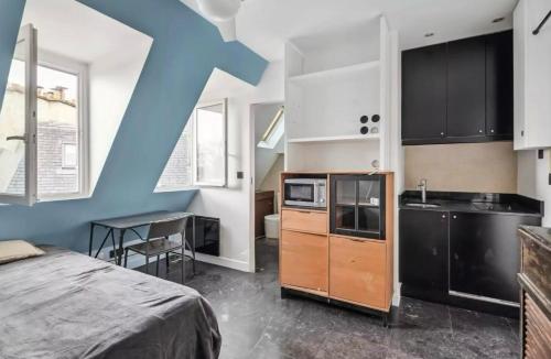 une chambre avec un lit et une cuisine avec des armoires noires dans l'établissement Fantastic Studio au Coeur de Paris, à 2 minutes du Musée d'Orsay, à Paris