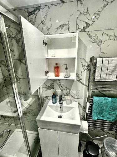 a white bathroom with a sink and a shower at Timex Studio in Croydon