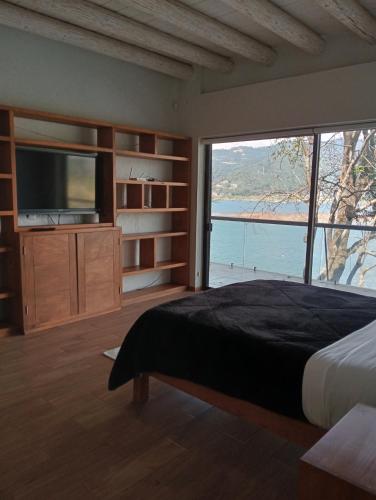 a bedroom with a large bed and a large window at La Casa del Lago in Valle de Bravo