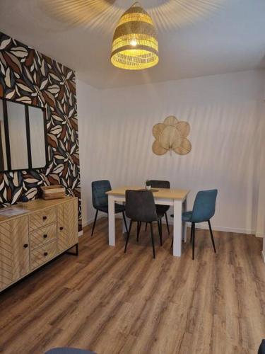 une salle à manger avec une table, des chaises et un lustre dans l'établissement Le Carnot, à Montceau-les-Mines