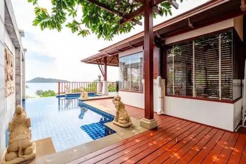 a house with a wooden deck with a swimming pool at Patong Seaview Luxury Villa Penda in Patong Beach