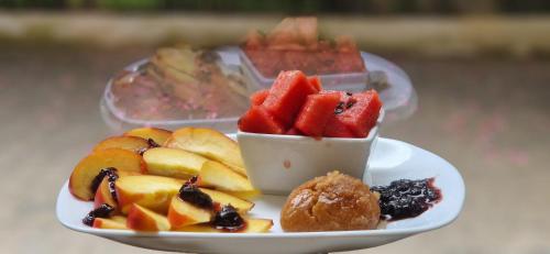 a plate of fruit on a table with a bowl of watermelon at The Honeycomb Boutique Hotel in Golem