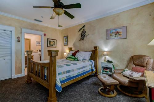 a bedroom with a bed and a chair and a ceiling fan at Anchor Inn NSB Bed and Breakfast in New Smyrna Beach