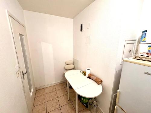 La petite salle de bains est pourvue d'un lavabo blanc et d'un réfrigérateur. dans l'établissement La source appart, à Orléans