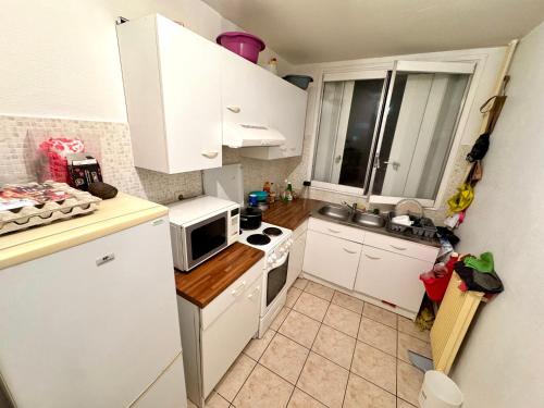 une petite cuisine avec des armoires blanches et un micro-ondes dans l'établissement La source appart, à Orléans