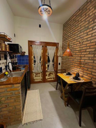 a kitchen with a table and a brick wall at Espaço da Zilda in São José