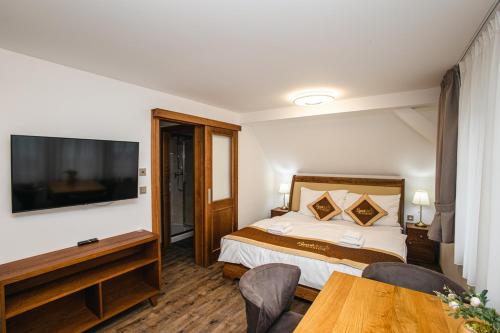 a hotel room with a bed and a television at SYNEK Pension in Špindlerův Mlýn
